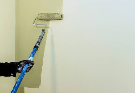 Home renovation project involves painting wall using paint roller in residential space during works day